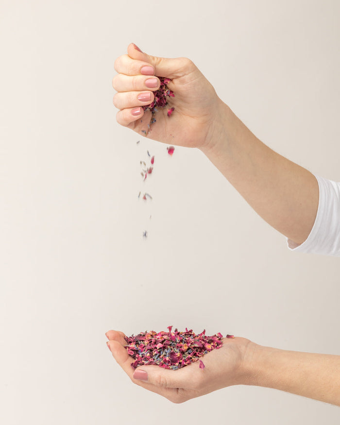 Mano dejando caer pétalos secos de rosa como alternativa al arroz en una boda